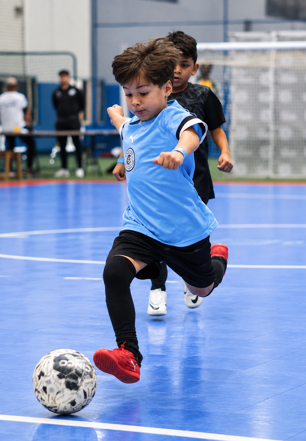 Youth futsal player in Cadence blue jersey dribbling the ball